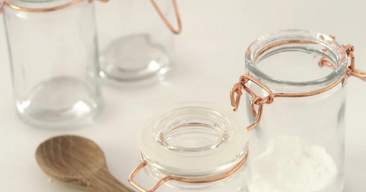 Open jar of baking soda on clean surface used as trash can odor absorber — works on surface smells but not baked-in bacterial residue