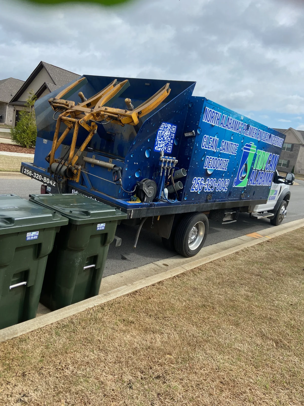TidyCan Alabama bin cleaning truck parked curbside beside residential trash cans in North Alabama